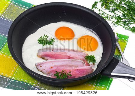 Fried eggs and bacon in frying pan on white background. Studio Photo