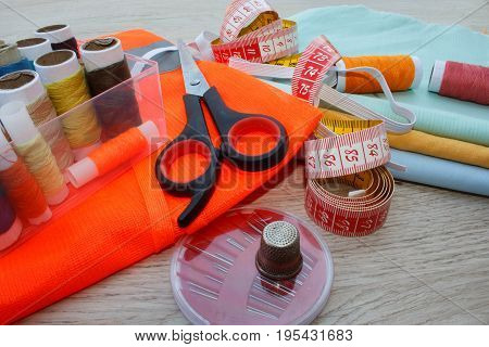 Sewing tools and sewing kit on wooden textured background. Sewing kit. Thread needles and cloth. tailor workspace with sewing and handmade tools