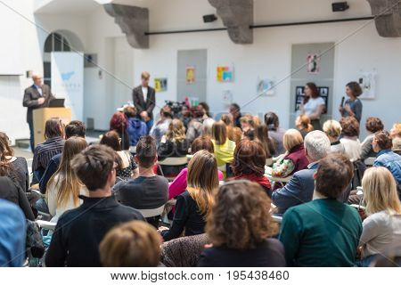 Male speaker giving presentation in lecture hall at university workshop. Audience in conference hall. Rear view of unrecognized participant in audience. Scientific conference event.