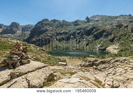 Stone Cairn Overlooking Lac De Melo In Mountains Of Corsica