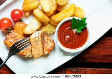 Vegetarian dinner. Fried tofu with spices, potatoes with fresh tomatoes. On a white plate, wooden background