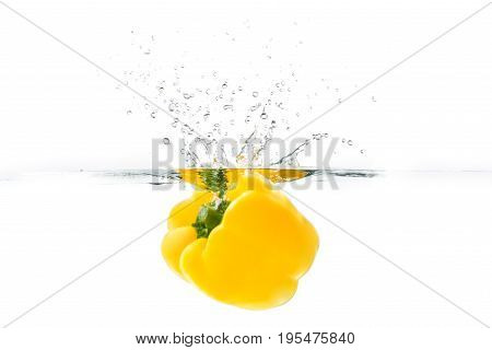 Yellow bellpepper dropped into the water with water splash on a white background
