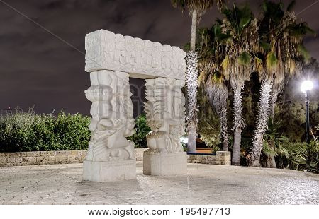 The modern contemporary sculpture "Statue of Faith" in Gan HaPisga Summit Garden with the biblical scenes by Daniel Kafri at night in old city Yafo Israel.