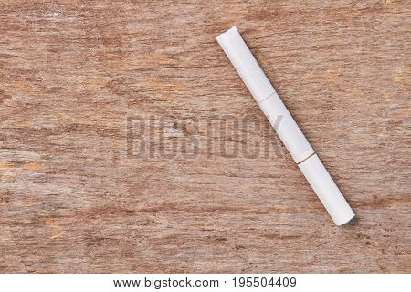 White tobacco cigarette on wooden background. Cigarette addiction leads to cancer of lungs.