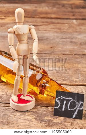 Human wooden model, bottle, message. Stop alcoholism concept.