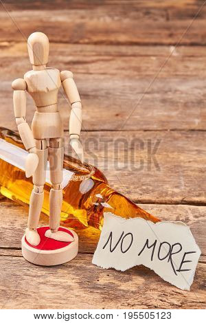 Human model dummy, alcohol, message. No more alcohol text, wooden human figurine, wooden background.