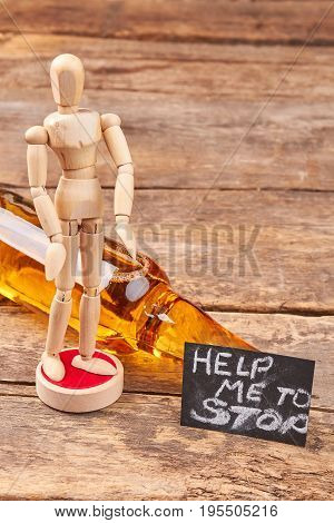 Alcohol addiction how to stop. Human wooden dummy, alcohol, message, wooden background.