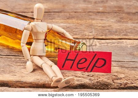 Stop drinking message, wooden dummy. Wooden puppet, transparent bottle, wooden background.