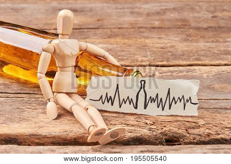 Human wooden figurine, alcohol beverage. Wooden dummy, image of heart beat, wooden background.