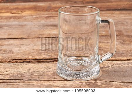 Empty glass mug, wooden table. Transparent glass for beer on wooden retro board.
