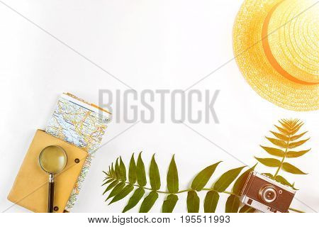 Straw hat with green leaves and old camera on white background, Summer background. Top view. Copy space. Still life. Flat lay. Sun flare