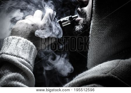 Vaping Man Holding A Mod. A Cloud Of Vapor. Black Background. Vaping An Electronic Cigarette With A
