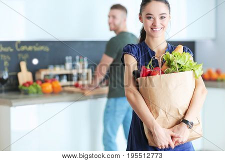 Young couple in the kitchen , woman with a bag of groceries shopping.
