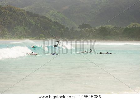 10/06/2017 Pantau Mawun Lombok Indonesia. Large group of tourists learn to surf on small beginner waves at a paradise tropical beach.