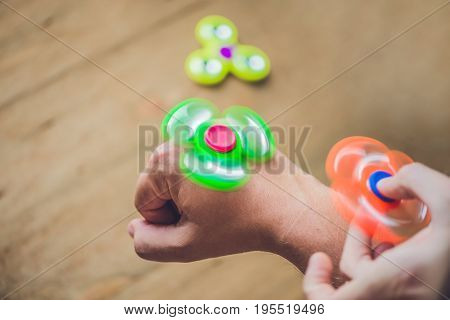 A Man Hand Holding Hand Spinner Or Fidget Spinner Over Wooden Background