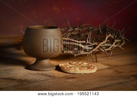 Communion table with bread and cup of wine and crown of thorns in background
