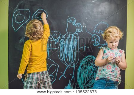 Boy And Girl Paint With Chalk On A Blackboard
