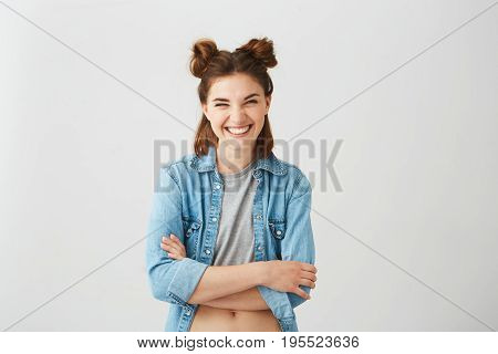 Portrait of cheerful happy young positive girl with buns looking at camera laughing smiling with crossed arms over wite background. Copy space.