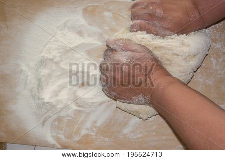 Top view shot of female hands mixing dough. Female hands knead dough on wooden board. 4k prores footage