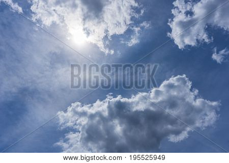 View on beautiful white Clouds on a blue Sky. Close-up of a cloudy Sky in the Morning. The Sun is shining from a blue Sky.