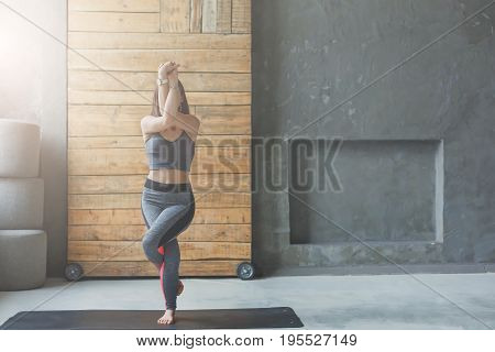 Woman in yoga class making asana exercises, copy space. Girl do eagle pose, garudasana. Healthy lifestyle in fitness club. Stretching