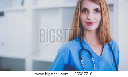 Happy doctor woman is standing in the near window