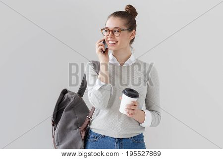 Studio Photo Of Student Girl Isolated On Grey Background With Backpack On Her Back, Holding Takeaway