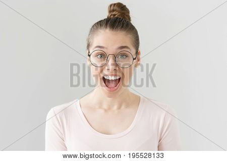 Indoor Shot Of Attractive Teenage Girl With Brown Hair Tied In Bun Isolated On Grey Background, Smil