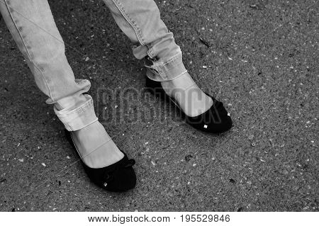 Women's Feet In Blue Jeans And Black Sneakers Close Up