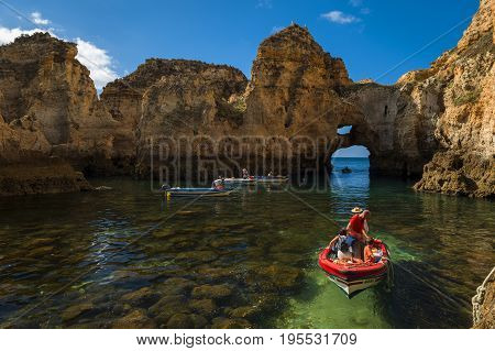 Ponta da Piedade Portugal - July 6 2017: Boats in the small bay between the sandstone cliffs at the Ponta da Piedade in Lagos Portugal