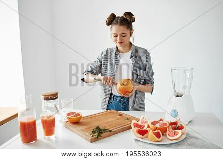 Girl making grapefruit juice or smoothie cutting fruits smiling. Healthy lefestyle concept.
