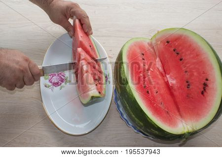 Men hand hold from on fresh watermelon cutting for eatin on table background. Male cutting a delicious sweet watermelon