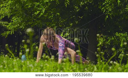 Young woman doing yoga exercises in the park. Ashtavakrasana