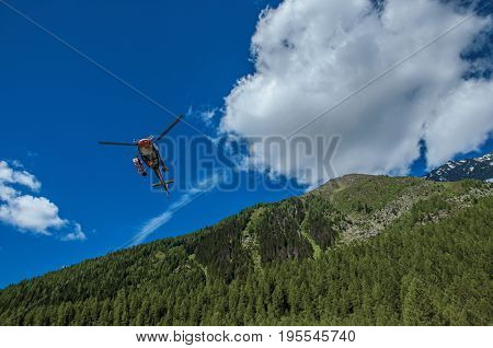 Argentière, France - June 27, 2016. Helicopter taking off in a forest at Argentière, a small alpine village with several ski routes in the winter and hiking in summer. Near Chamonix in the French Alps