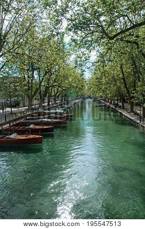Large canal with boats and trees in the city center of historic Annecy. Located in the Haute-Savoie department, south-eastern France.