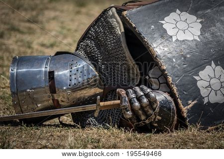 Medieval knight fallen in battle, on a reenactment with costumed characters and medieval armor with chainmail, helmet swords and shields. Medieval demonstration and recreation