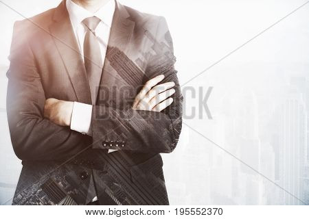 Businessman with folded arms on abstract city background with copy space. Future concept. Double exposure