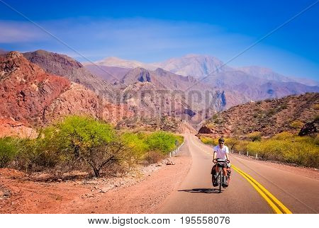 Man cycling on the empty road to Cafayate in the remote part of north west Argentina