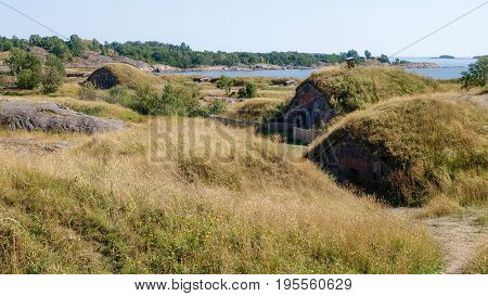 Old scandinavian earthen homes integrated into the rolling hills with the baltic sea in the back