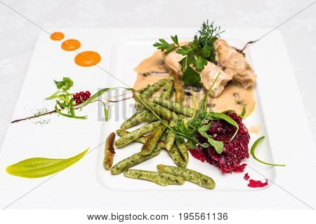 Side view beet salad with chicken meat in sauce decorated in white plate. Restaurant meal.