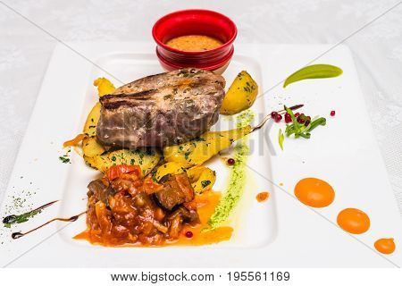 Side view bovine meat with potato and sauce decorated in white plate. Restaurant meal.