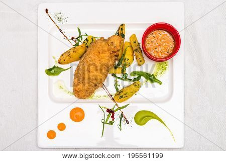 Top view chicken meat with potato and sauce decorated in white plate. Restaurant meal.
