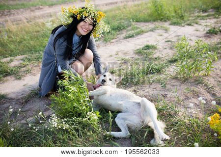 Dog owner playing with her favorite dog. Beautiful oriental young woman wearing fower wreath walking with dog.