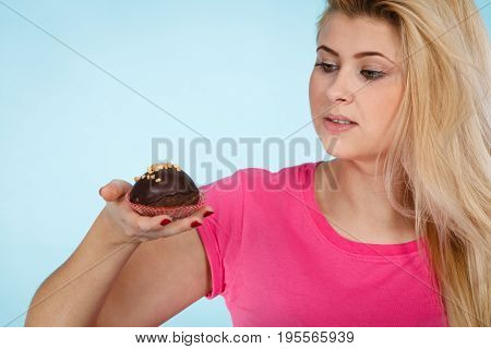 Diet sweets food concept. Woman holding delicious chocolate cupcake with peanut frosting about to take bite