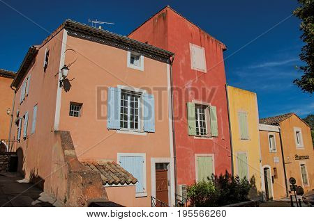 View of traditional colorful houses in ocher under a sunny blue sky, in the city center of the village of Roussillon. Located in the Vaucluse department, Provence region, in southeastern France