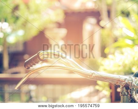 Scene of a retro bicycle handlebar on the way in public park with sunlight in summer or spring seasons.Vintage retro style and blur green tree bokeh for copy space.