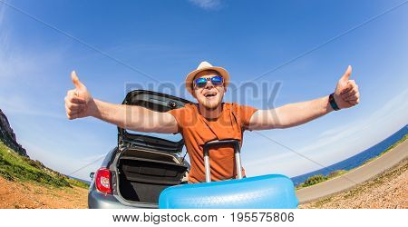 Summer, holiday, trip and vacation concept - Happy funny man near the car showing thumbs up and ready to travel