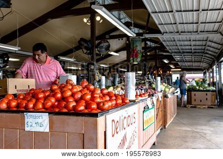 Clanton Alabama USA - June 17 2017: An employee at Durban Farms Market restocks tomatoes in the display case.