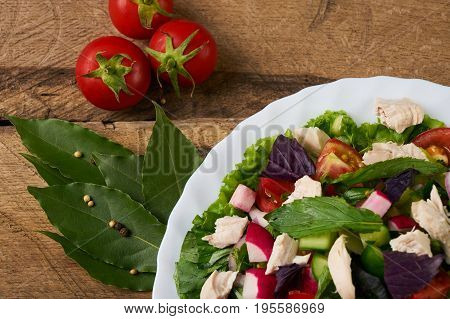 Fresh salad with chicken breast radish cucumber tomato onion bell pepper basil mint and other spices on old rustic wooden table. Copy space. Healhy eating. Top view