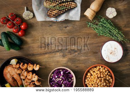 Vegetables, fish, and ingredients for cooking. Tomatoes, cucumber, white sauce. Top view on wooden table with copy spce
